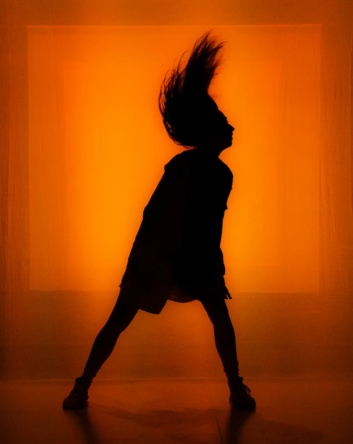 Una danzatrice in controluce davanti a uno sfondo arancione