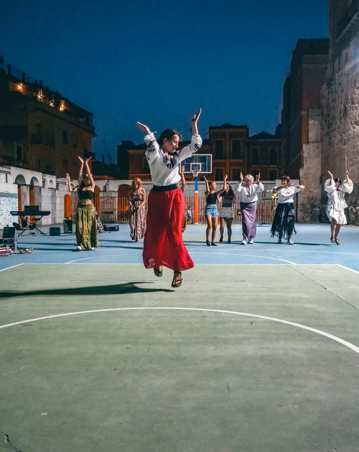 Una performance collettiva in piazza, con una danzatrice in gonna rossa
